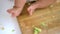 Baby feet covered with avocado on wooden board