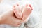 Baby feet in mother hands. Tiny newborn baby`s feet on female shaped hands closeup. Mom and her child