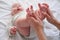 Baby feet in mother hands. Young caucasian woman makes massage for happy infant baby on white bed at home. Babycare