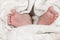 Baby feet on soft white coverlet. Adorable Toes. Close-up. Tiny bare feet of a little newborn baby girl or boy wrapped