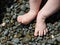 Baby feet standing on wet pebble