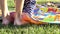 Baby Feet Walk on a Multicolored Coverlet Placed on a Green Lawn