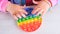 baby female hands playing with pop it sensory toy circle form. little female presses colorful rainbow squishy soft