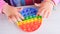 baby female hands playing with pop it sensory toy circle form. little female presses colorful rainbow squishy soft