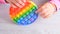 baby female hands playing with pop it sensory toy circle form. little female presses colorful rainbow squishy soft