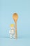 A baby figurine with a large wooden spoon on a blue background