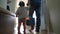 baby first steps with dad. happy family a kid dream concept. dad and baby daughter walk along the corridor of the house