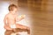 Baby on the floor of his house in diapers, holding his first liquid yogurt in a plastic pot