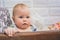 A baby with a frightened worried look sits on a chair