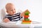 Baby game. Little clever caucasian child playing colorful wood toys making house or tower of cubes on highchair. games