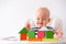 Baby game. Little clever caucasian child playing colorful wood toys making house or tower of cubes on highchair. games