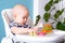 Baby game. Little clever caucasian child playing colorful wood toys making house or tower of cubes on highchair. games