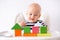 Baby game. Little clever caucasian child playing colorful wood toys making house or tower of cubes on highchair. games