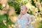 Baby in the garden. Angel girl eat plum. Summer sunny day. Green blurred background in the background