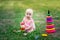 Baby girl 10 months old sitting on the grass in the summer and playing pyramid, early development of children, outdoor games