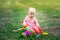 Baby girl 10 months old sitting on the grass in the summer and playing pyramid, early development of children, outdoor games