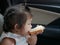 A baby girl, 2 years old, learning to eat, by herself, a sheet of white bread with sweetened condensed milk on top in a car during