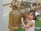 A baby girl, 3 years old, enjoys ringing big temple bells as the sound of the bell is considered auspicious