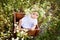 A baby girl 7 months old sitting on a chamomile field in a wreath in a white dress, a healthy walk in the fresh air