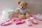 Baby girl accessories diapers and clothes  teddy sitting on pink color floor