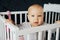 Baby girl with blue eyes and blond standing in her bed