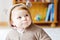 Baby girl with blue eyes wearing brown bear winter overal in sunny bedroom. Newborn child being dressed for an outdoor