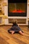Baby girl crawling near the electric fireplace.