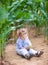 Baby girl with curly hair in field playing with corn