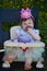 Baby girl eating first birthday cake with purple frosting and pink crown on her head