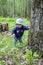 Baby girl in a hat and jeans surprised face. Baby 9 months exploring the forest grass and trees. First steps in nature