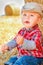 A Baby girl on a haystack happy on the field. Background with children a joyful childhood