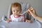 Baby girl in high chair eating her baby food