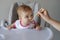 Baby girl in high chair eating her baby food