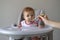 Baby girl in high chair eating her baby food