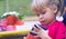 Baby girl holding a mobile phone. Little Caucasian girl playing with smartphone in summer park. Child learning how to