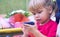 Baby girl holding a mobile phone. Little Caucasian girl playing with smartphone in summer park. Child learning how to