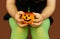A baby girl holds a pumpkin on her lap. A little girl dressed in green tights for Halloween holds a pumpkin lantern in her hands c