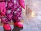 Baby girl legs in pink galoshes, overall and part of hands in gloves