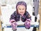 Baby girl lies on playground slide during snowfall. Happy kid having fun plays with snow