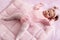 Baby girl lying on a pink duvet