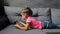 Baby girl lying on sofa with tablet. Little girl lying playing on tablet