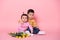 Baby girl and older brother boy on pink studio background. Cheerful happy kids with tulips flower bouquet