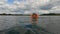 Baby girl in an orange inflatable vest is swimming in the lake