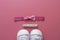 Baby girl pink background with newborn shoes, bow and Welcome words. Baby flat lay