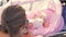 Baby girl in pink bassinet and mother browsing web on cell outdoor