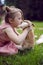 baby girl in a pink dress kiss rabbit in a green meadow in summer. Funny friendship between a child and an animal during