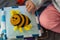 Baby girl playing with her textile book. Pages with funny felt bee, woolly rainbow and sun. Baby development. Educational toys.