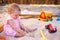 Baby girl playing in sandbox on outdoor playground. Child with colorful sand toys. Healthy active baby outdoors plays games