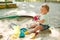 Baby girl playing in sandbox on outdoor playground. Child with colorful sand toys. Healthy active baby outdoors plays games
