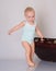Baby girl playing with suitcase on grey background